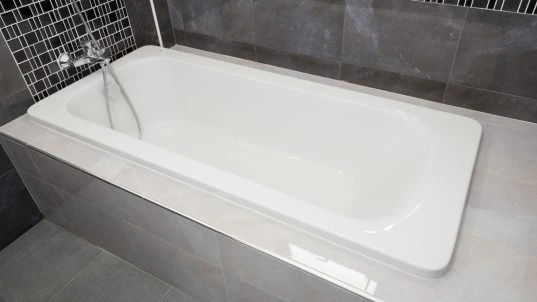 Weisse Badewanne in grauem Badezimmer