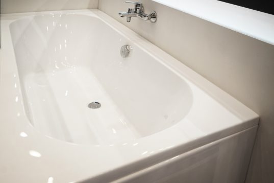 Weisse Badewanne mit mittig ausgerichteten Armaturen